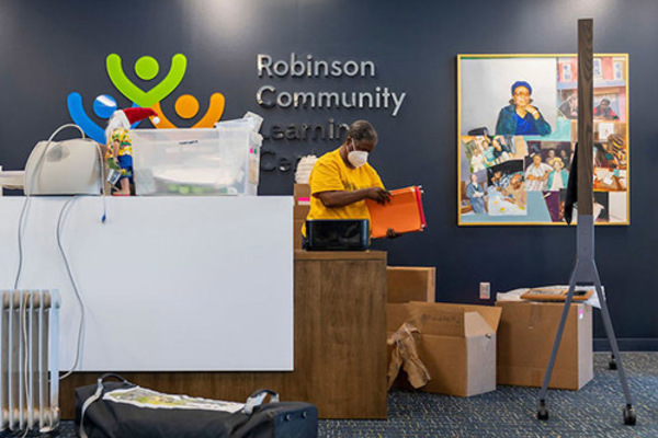 A staff member is unpacking file folders in front of a wall with a Robinson Community Learning Center sign