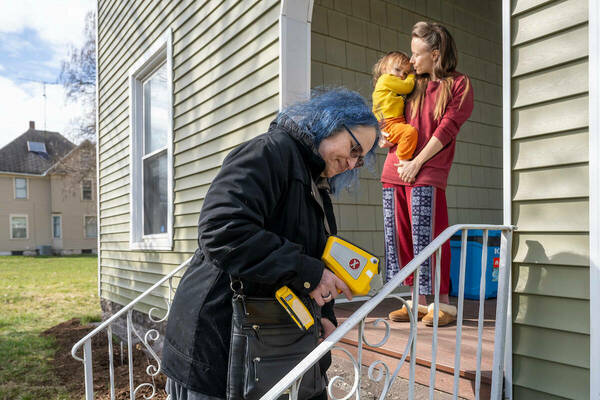 Chemistry professor Marya Lieberman, one of the founders of ND-LIT, uses a handheld instrument to scan soil and painted surfaces for lead. She found elevated levels on lead on the painted iron railing of the home of Sally Geislar, on the porch with her two-year-old son. (Photo by Barbara Johnston, University of Notre Dame)