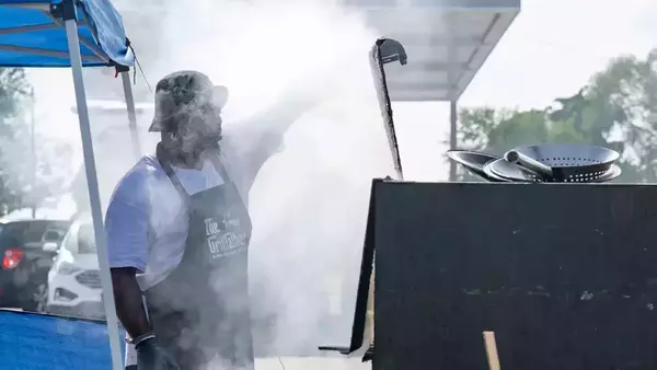 Entrepreneur Raymond Barbour stands in front of his port-a-pit grill while smoke envelopes his face.